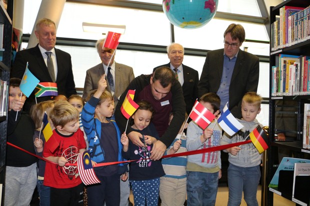 Eröffnung Internationale Bibliothek - Kinder halten verschiedene Landesflaggen und schneiden gemeinsam mit Vertretern das Eröffnungsband durch