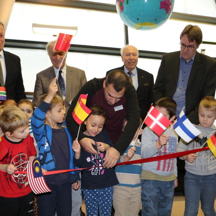 Eröffnung Internationale Bibliothek - Kinder halten verschiedene Landesflaggen und schneiden gemeinsam mit Vertretern das Eröffnungsband durch (vergrößerte Bildansicht wird geöffnet)