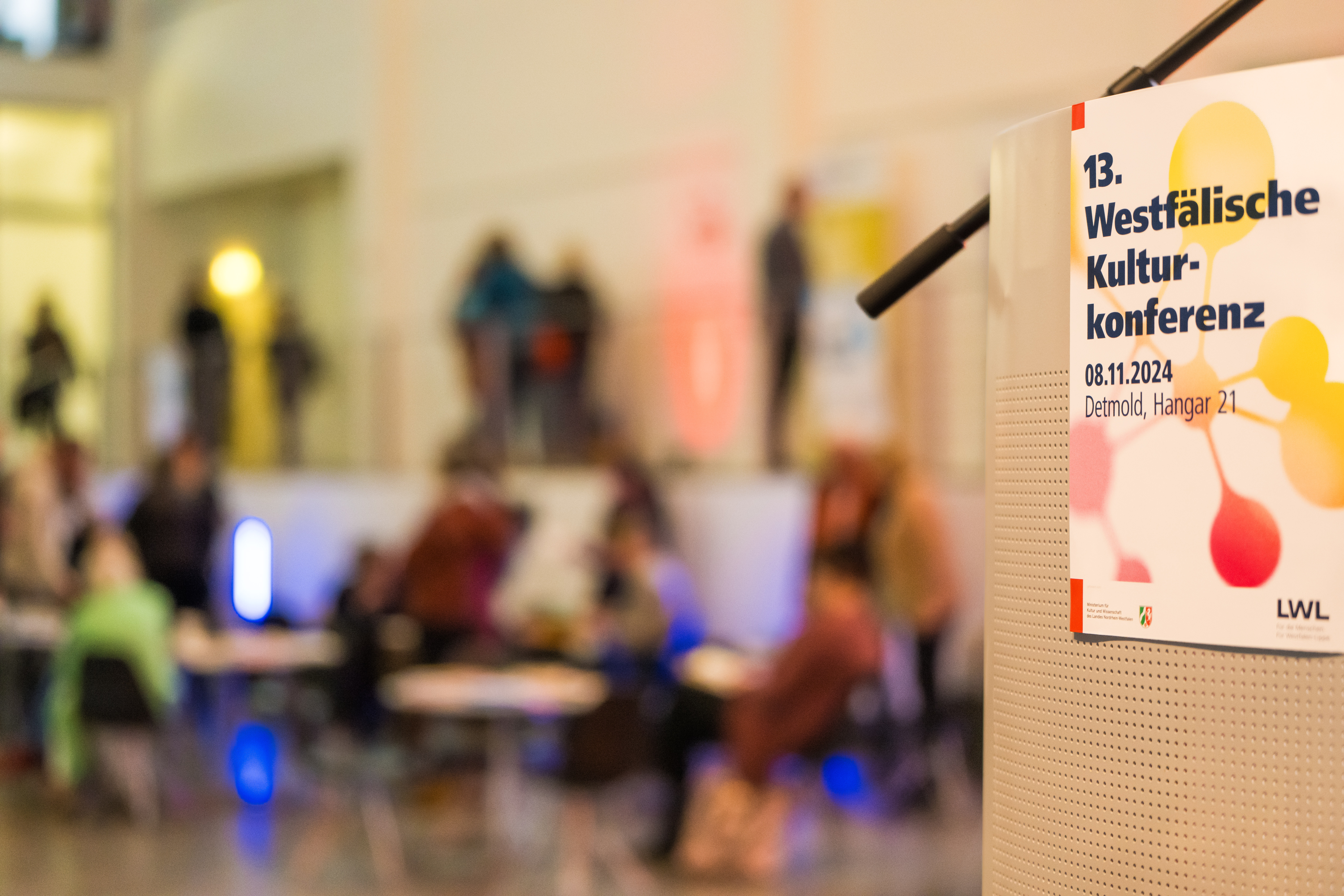 Ein Plakat der 13. Westfälischen Kulturkonferenz im Vordergrund. Der Hintergrund ist unscharf. Ein Plakat der 13. Westfälischen Kulturkonferenz im Vordergrund. Der Hintergrund ist unscharf.