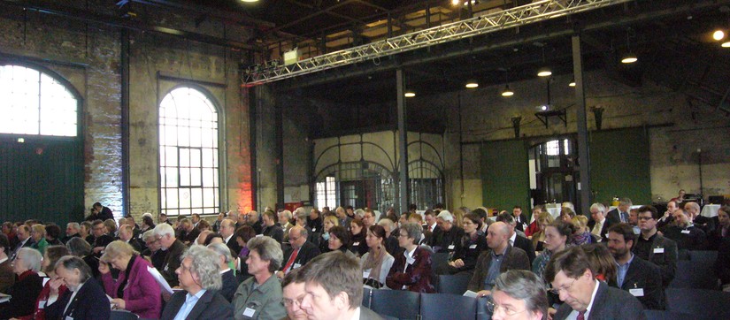 Bild mit Blick in den Veranstaltungsaal mit den Teilnehmer:innen