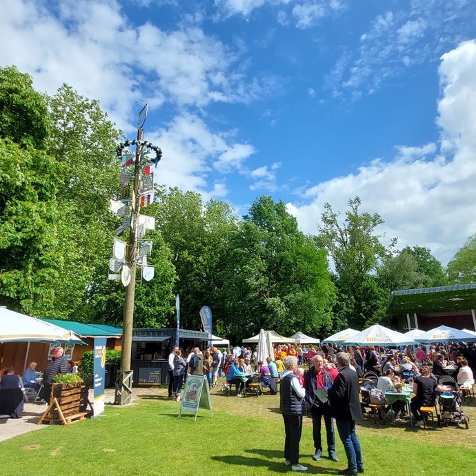 Zum Frühlingsfest geschmückter Festplatz auf einer Wiese mit vielen Menschen (vergrößerte Bildansicht wird geöffnet)