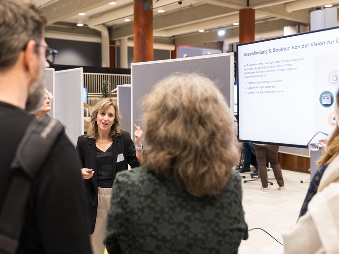 KI-Werkstatt-Referentin Rafaela Aulbach mit Konferenzteilnehmer:innen (vergrößerte Bildansicht wird geöffnet)
