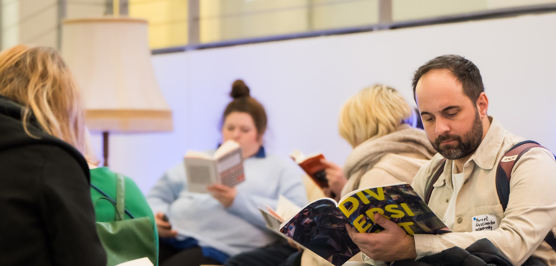 Personen lesen Bücher und Broschüren in der Lese-Ecke.