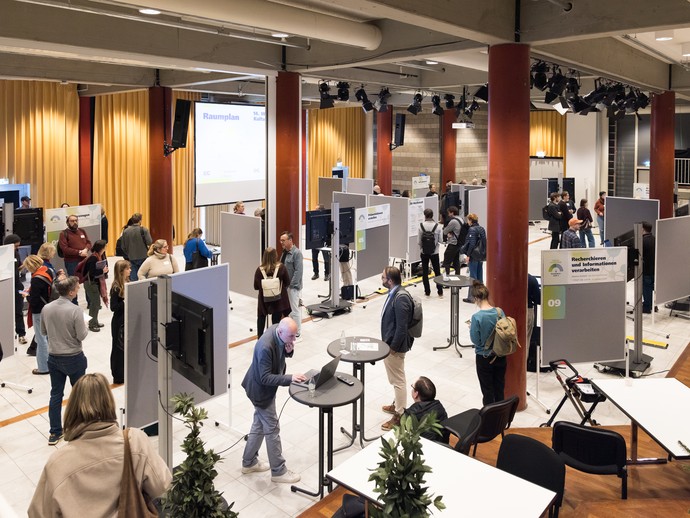 Menschen stehen in der KI-Werkstatt (vergrößerte Bildansicht wird geöffnet)