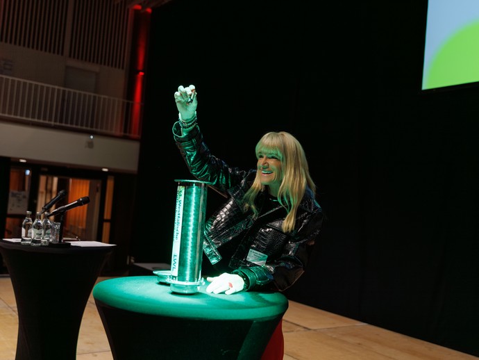 Dr. Barbara Rüschoff-Parzinger befüllt die Zeitkapsel mit den digital gesicherten Beiträgen der Konferenzteilnehmer:innen (vergrößerte Bildansicht wird geöffnet)