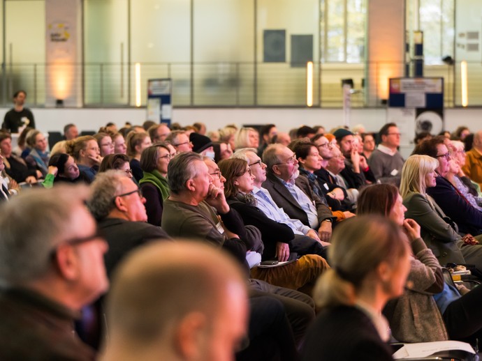 Menschen sitzen im Plenum. (vergrößerte Bildansicht wird geöffnet)