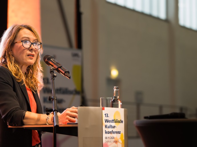 Eine Person hält einen Vortrag. (vergrößerte Bildansicht wird geöffnet)